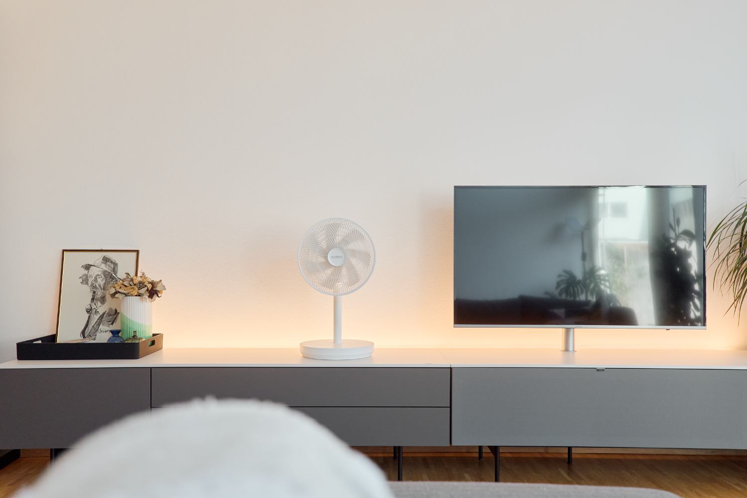 Ventilateur ecoQ SilenAir Due+ sur un buffet à côté d'un téléviseur dans un salon minimaliste